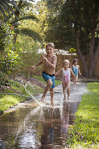 在花园人行道上玩水的儿童图片