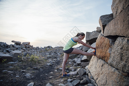 女人抬起腿在岩石上拉伸图片
