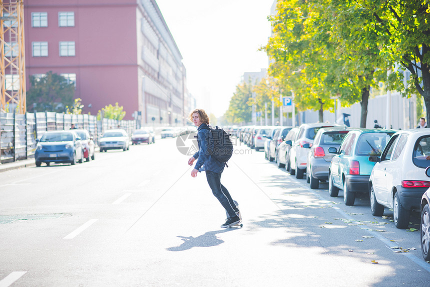 年轻男城市滑板运动员在路上滑滑板图片
