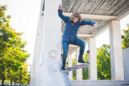 城市中的年轻男滑板运动员在混凝土结构下滑滑板图片