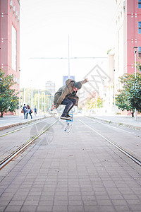 年轻男滑板运动员在车轨上跳滑板图片