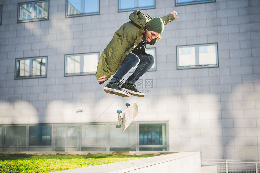城市青年男子滑板运动员在空中滑滑板图片