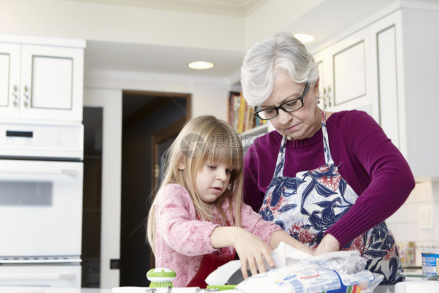 女孩和祖母在烘烤盘中铺防油纸图片