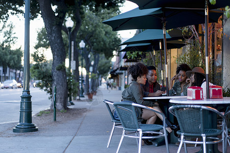 坐在咖啡厅外面餐桌看手机的一群女人图片