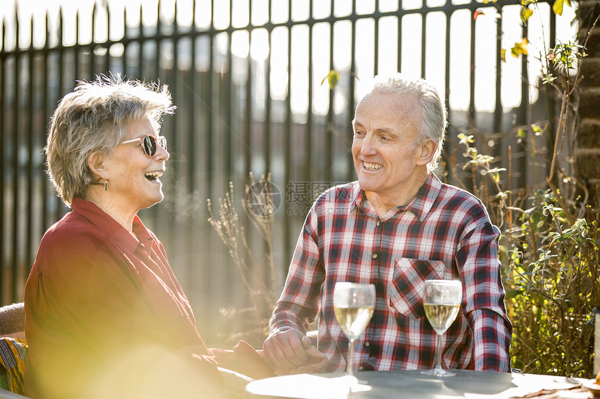 住在屋顶花园的老夫妇闲聊喝白葡萄酒放松图片