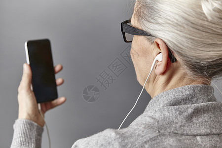 用手机听歌的老妇人背景图片