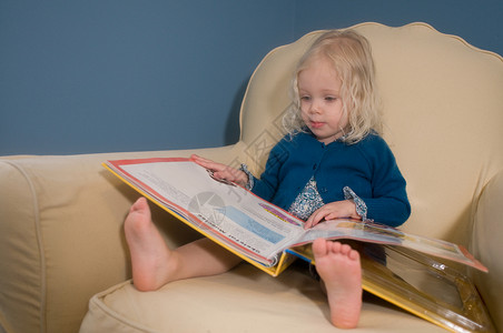 年轻女孩坐在扶手椅上看书图片