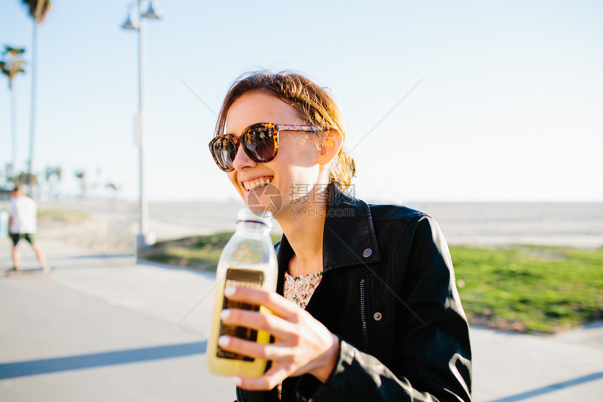 美国加利福尼亚州威斯海滩岸带果汁的年轻女子图片