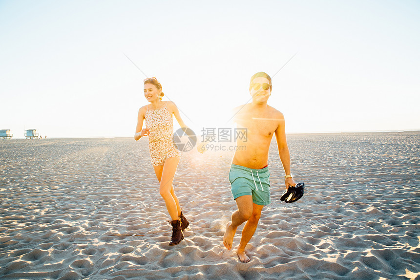 海滩上穿着游泳服和短裤的年轻夫妇图片