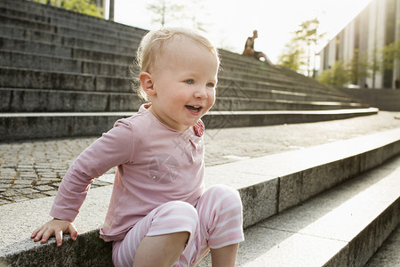 户外坐在台阶上微笑的小女孩图片
