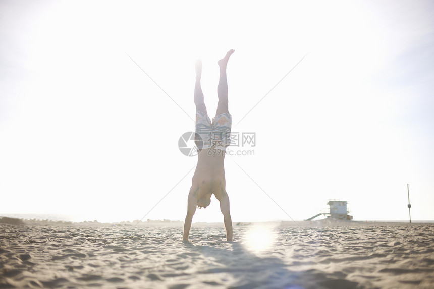 中年男子在沙滩上倒立图片