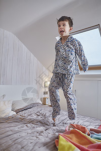 次日达穿着睡衣的男孩在阁楼的床上跳背景