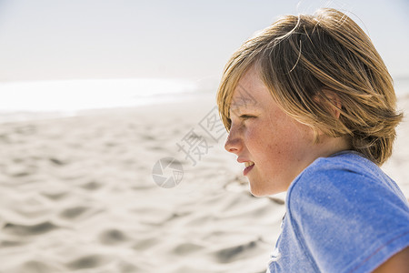 海滩上男孩向远处看的侧视图背景图片