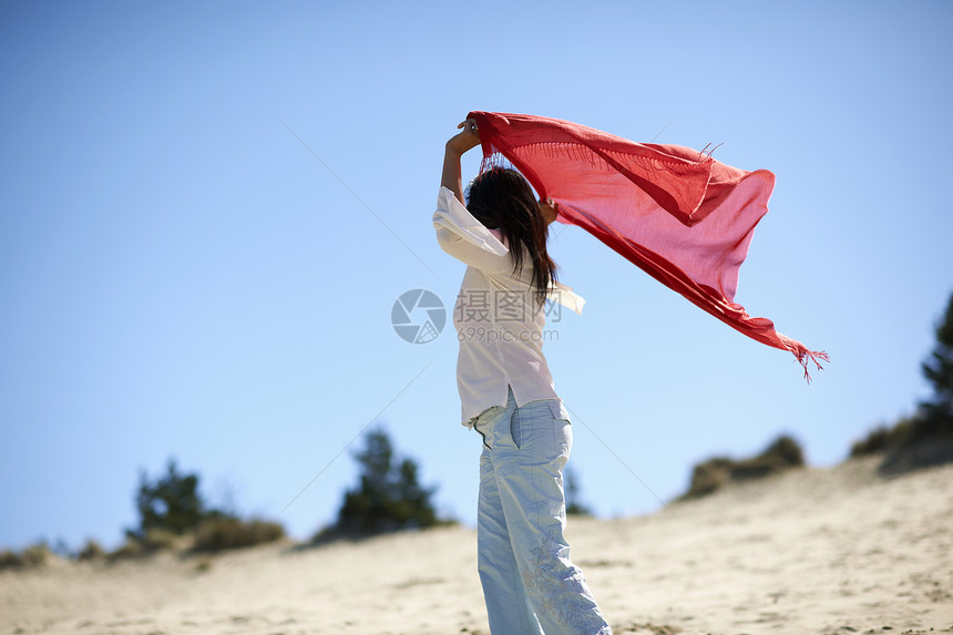穿着红披巾的女人享受海滩图片