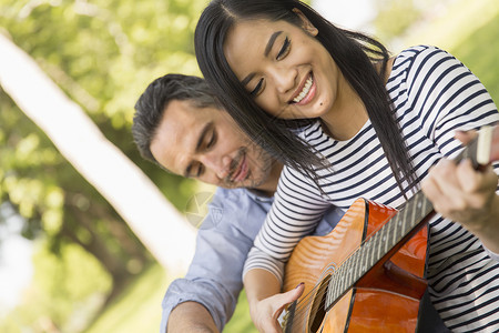 坐在草地上弹声吉他的女人微笑图片
