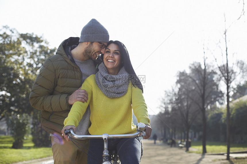 在公园的自行车上拥抱着笑的中成年女子男图片