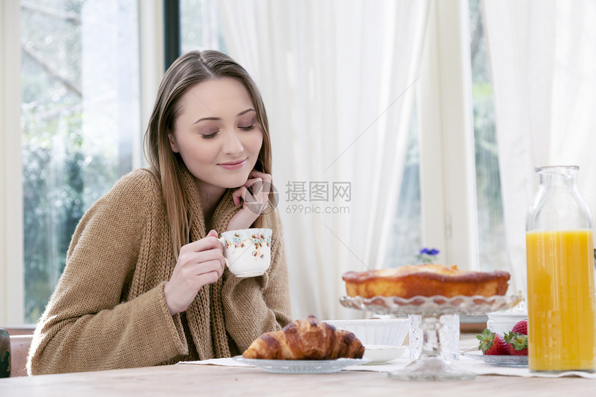 拿着茶杯闭上眼睛微笑的年轻女性图片