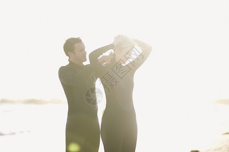 在美国加利福尼亚州日光威斯海滩上穿湿衣服的一对冲浪夫妇图片