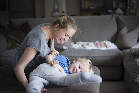 母亲和儿子在客厅里胡闹笑着小婴儿在睡觉图片