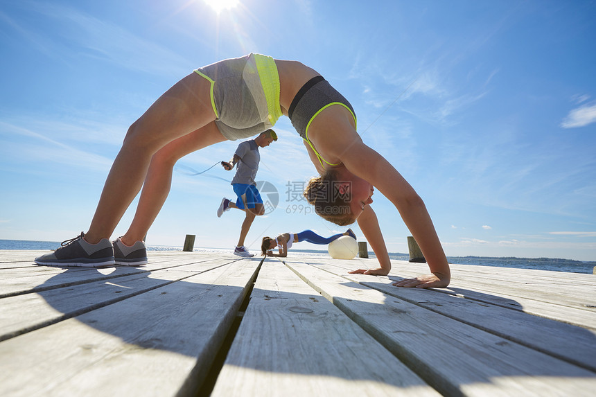 女人和朋友在码头上锻炼腰腹力量图片
