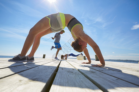拱背女人和朋友在码头上锻炼腰腹力量背景