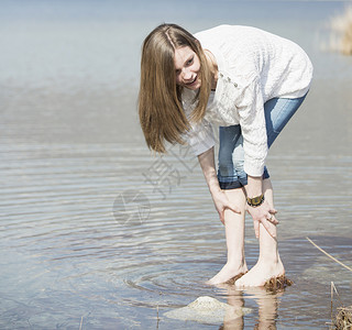 穿牛仔裤的少女在水池边玩水图片