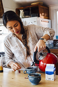 妇女从水壶里往茶杯里倒热水图片