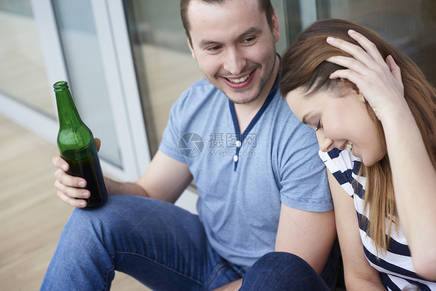 坐在户外喝瓶装啤酒的年轻夫妇图片