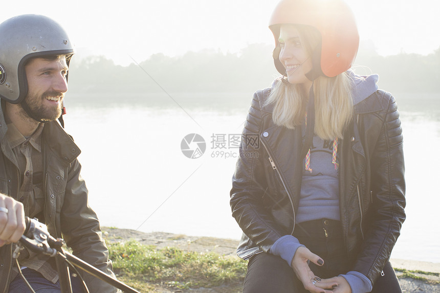 男人坐在摩托车上和年轻女人笑着说话图片