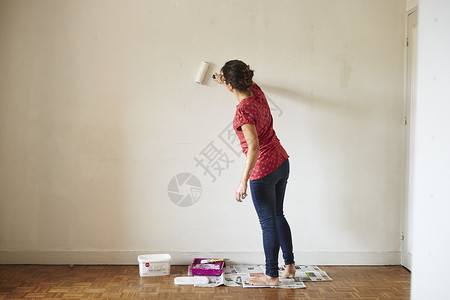 妇女在用滚筒粉刷墙面图片