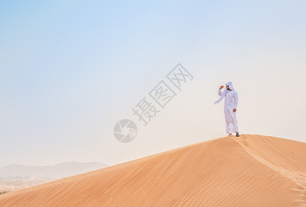 身着传统服装的中东男子站在阿拉伯联合酋长国迪拜沙丘上图片