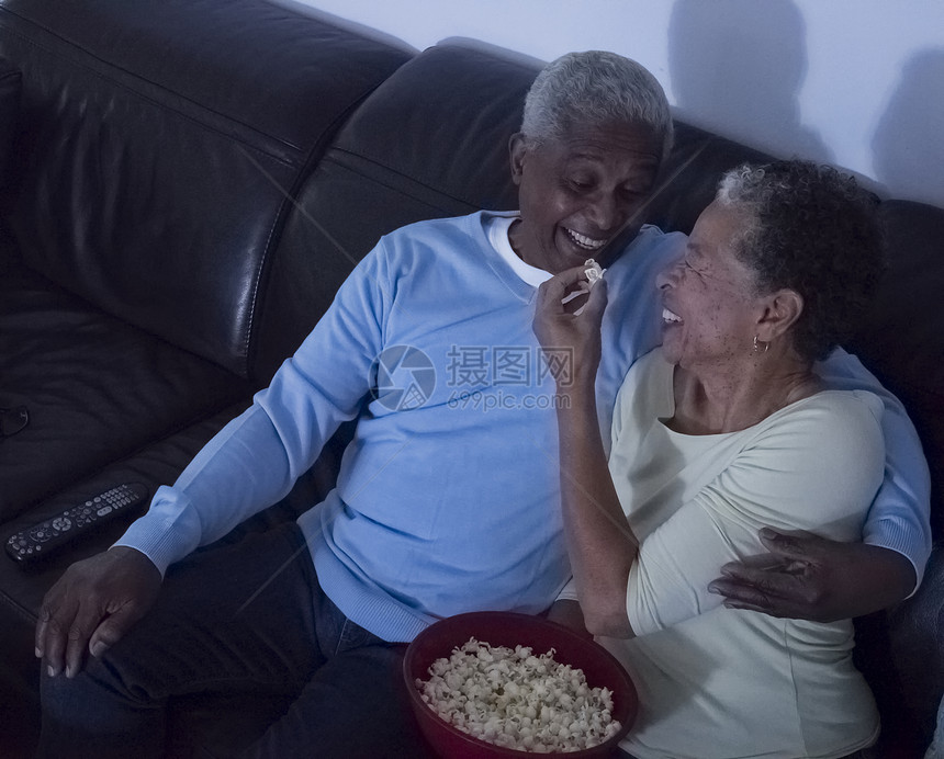年长夫妇坐在沙发上妻子喂给丈夫爆米花图片