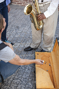 行人将钱扔进街头音乐家的音乐盒中图片