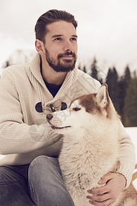 雪中抱着宠物狗的成熟男性图片