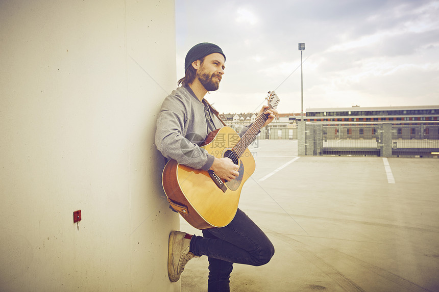 在屋顶停车场玩吉他的男人图片