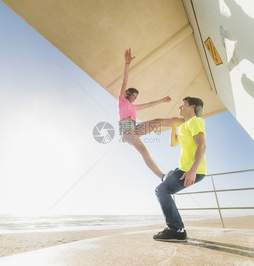在海滩救生员塔上做伙伴瑜伽的情侣图片