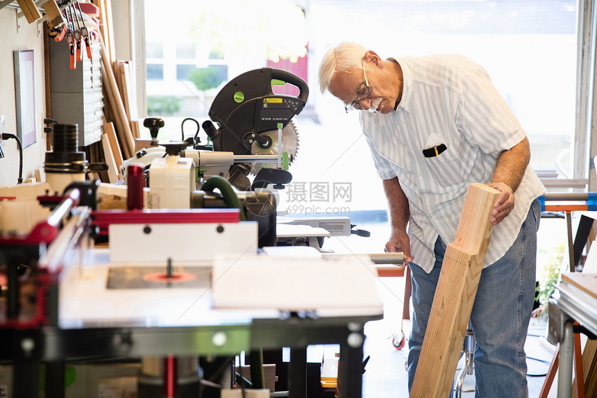 在木工车间检查板块的年长男子图片