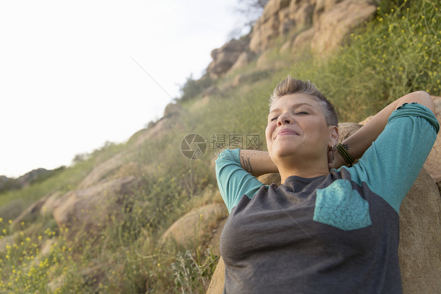 女人靠在岩石上眼睛闭着双手在头后图片
