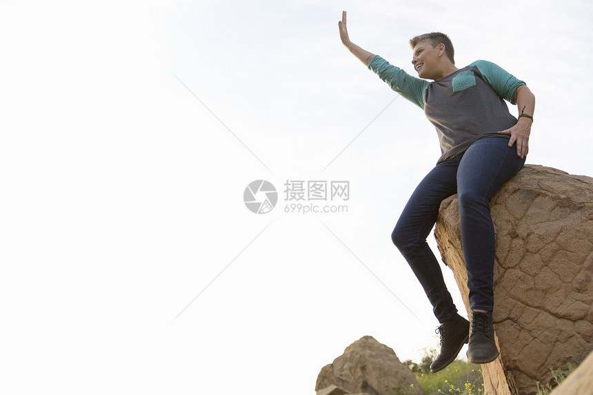 坐在岩石上四处挥舞的女子徒步旅行者图片