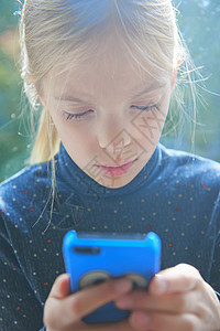 女孩在花园阅读智能手机短信图片
