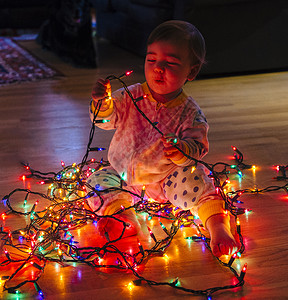 女孩在地板上玩圣诞节灯图片