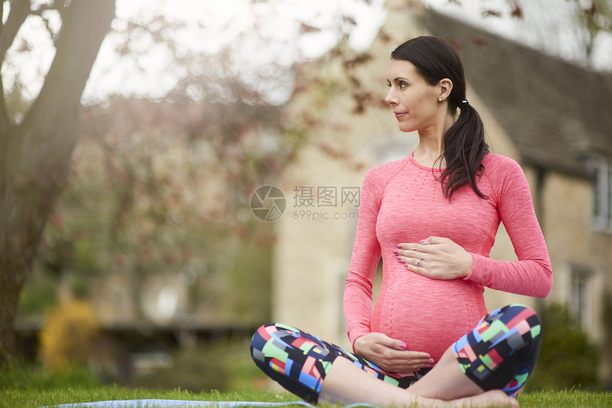 孕妇坐在草坪上抱着肚子图片