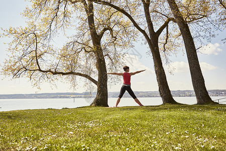 在湖边草坪上做瑜伽的女性高清图片