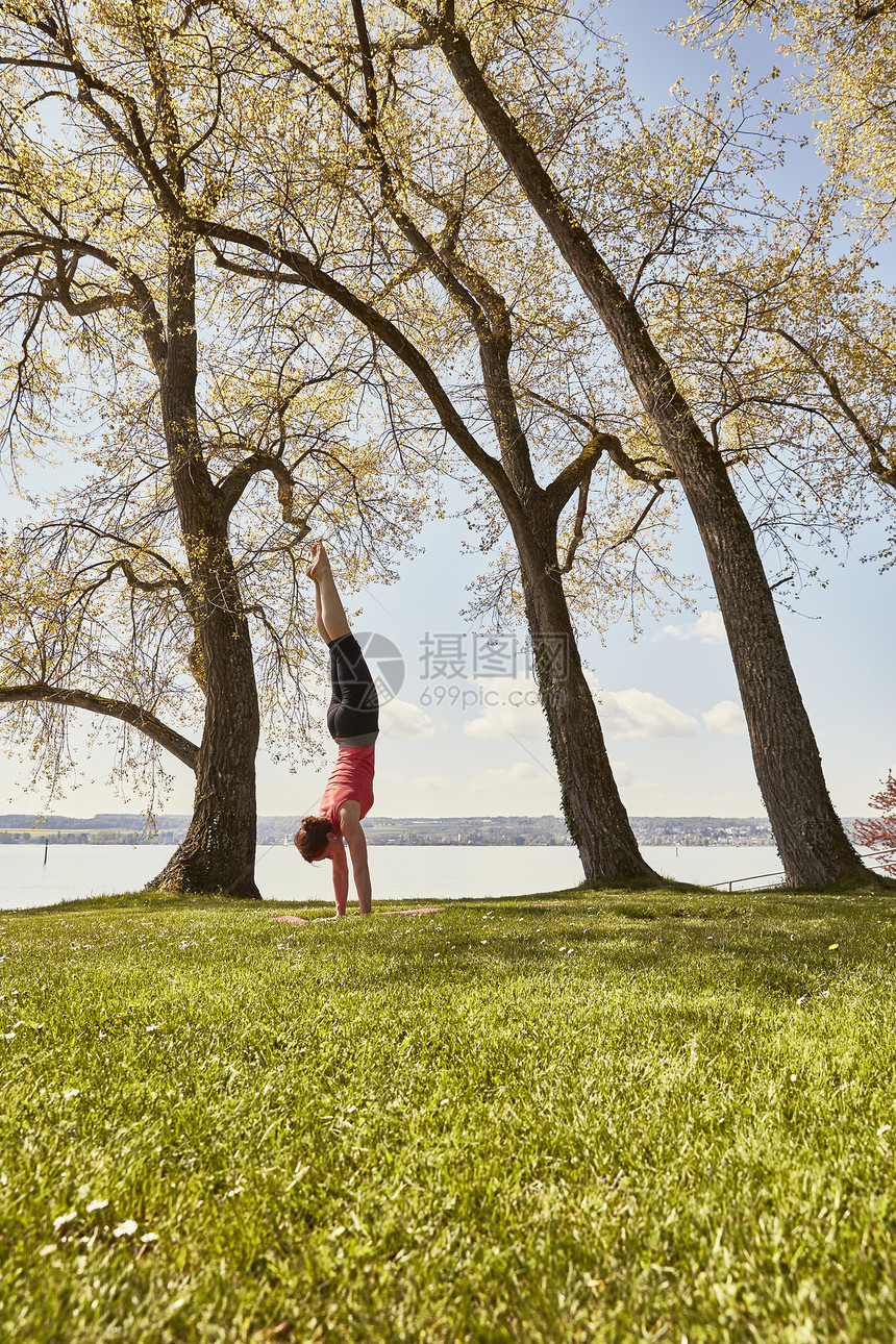 在湖边草坪上做瑜伽的女性图片