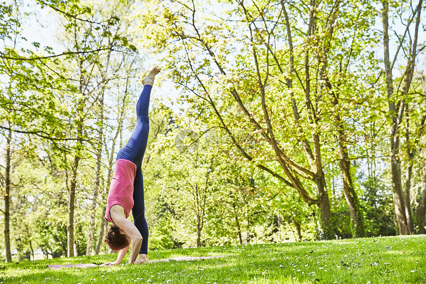 公园草坪上做瑜伽的年轻女性图片