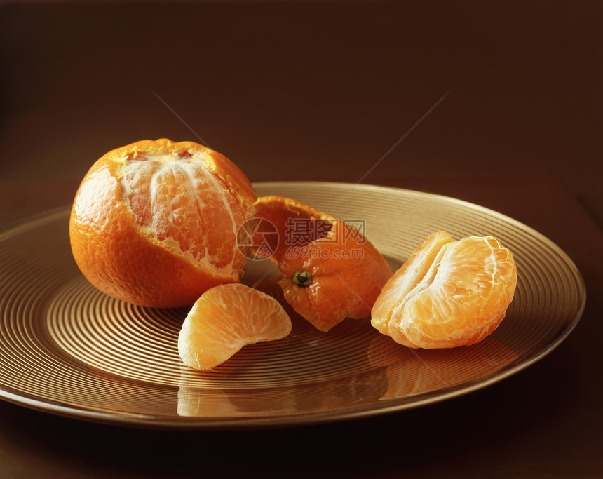 金色水果盘上的被拨开的橘子图片