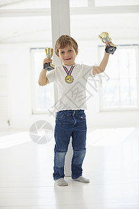 男孩举着奖杯戴着奖牌图片