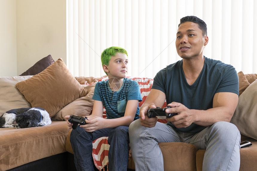 父亲和儿子在沙发上玩游戏图片