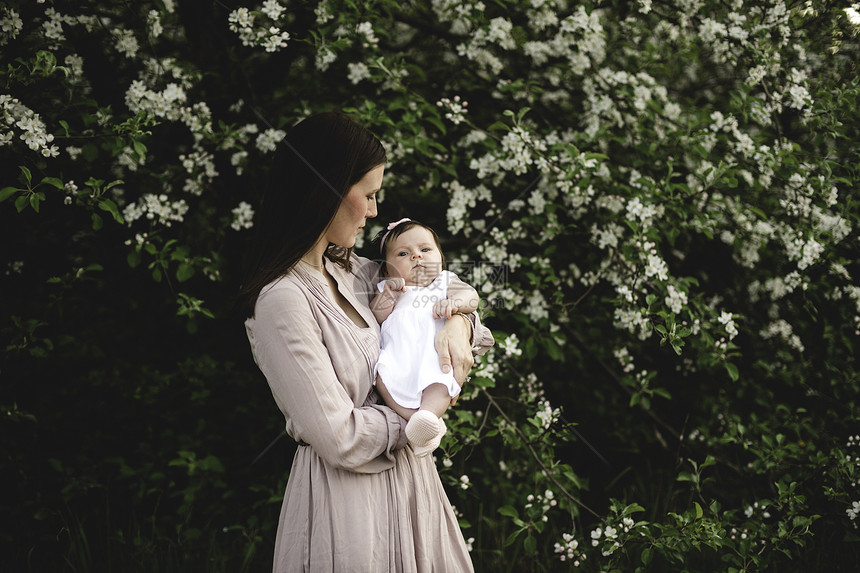 花丛前抱着女婴的中年妇女图片