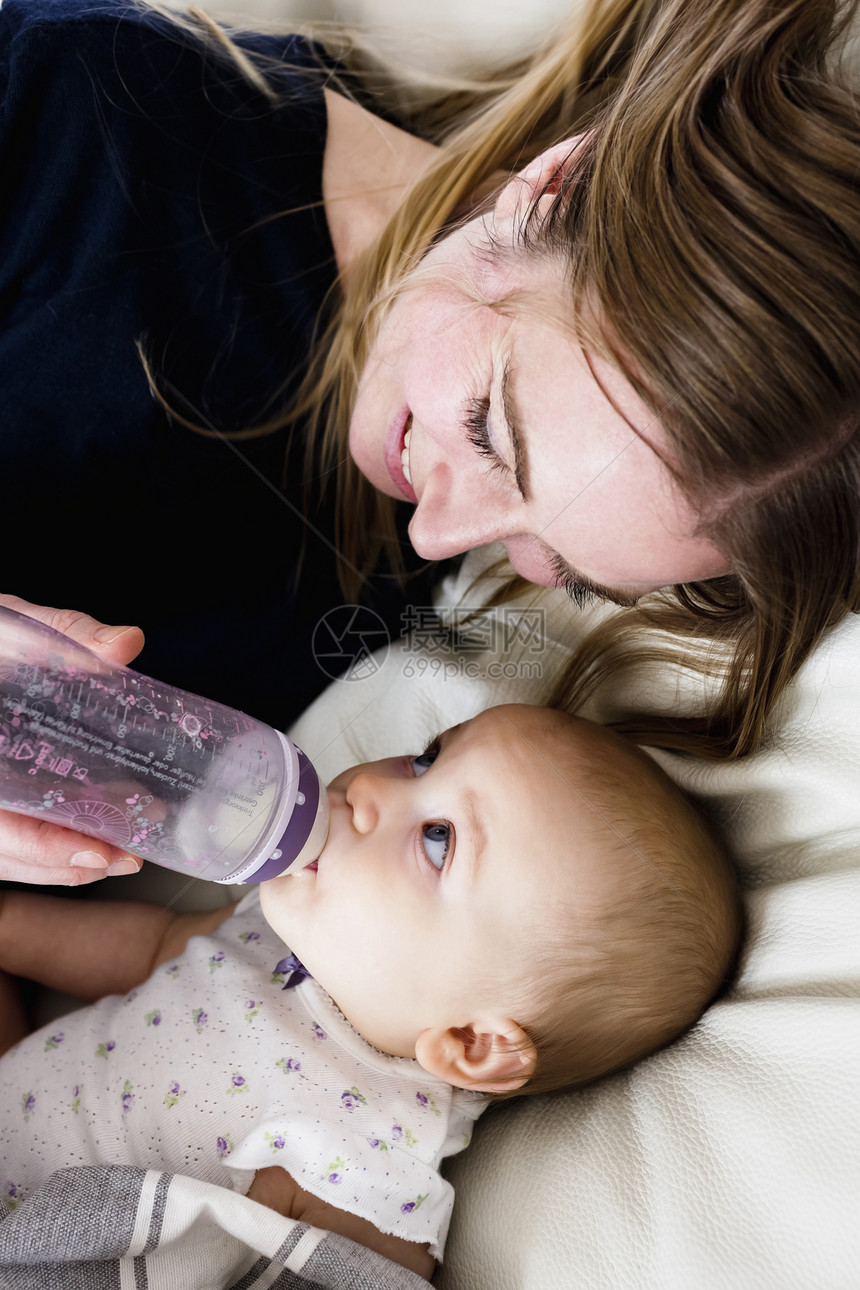 在沙发上喂婴儿吃奶的妇女图片
